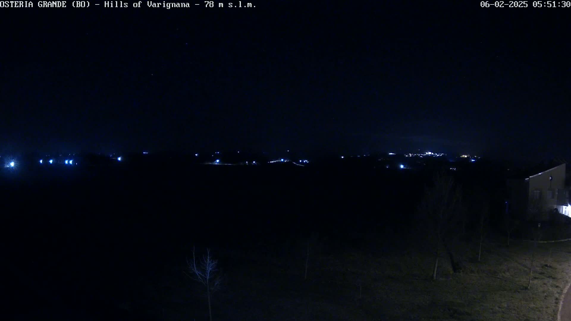 A nighttime view of a dark landscape with sparsely scattered lights in the distance under a clear, starlit sky.