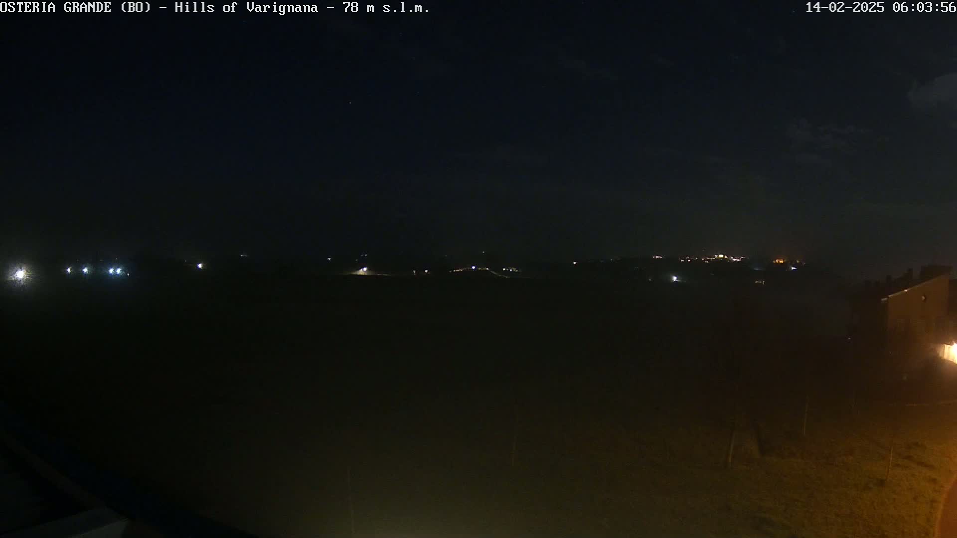 A dark, nighttime landscape shows dimly lit hills in the distance under a clear, starlit sky.