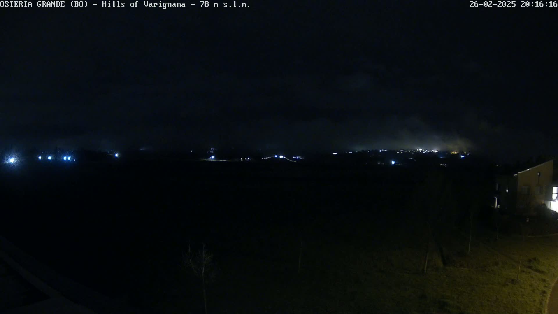A nighttime, low-light view of a dimly lit landscape with a hazy sky and some distant lights.