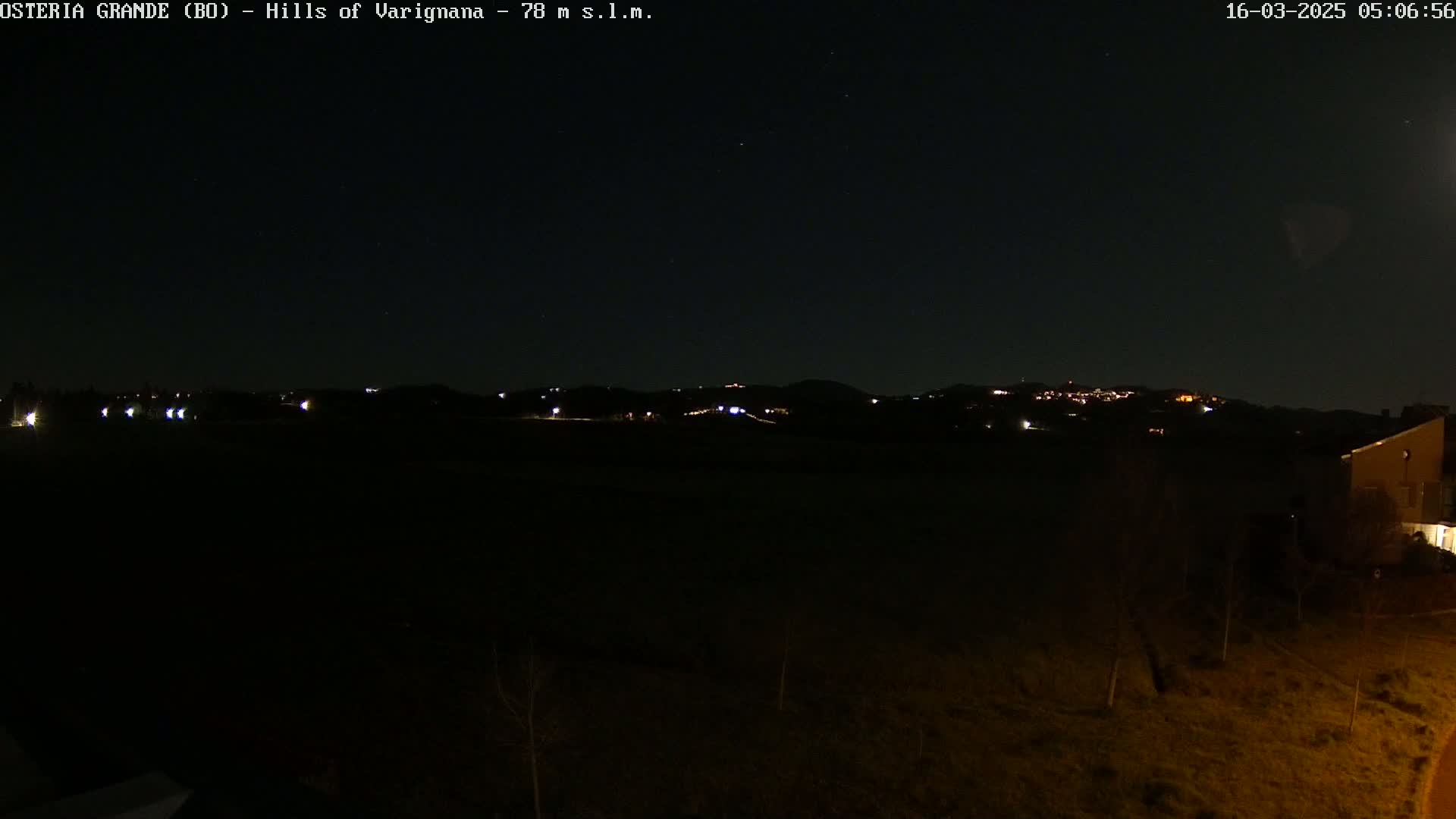A nighttime view of dimly lit hills in the distance, under a clear, starry sky.