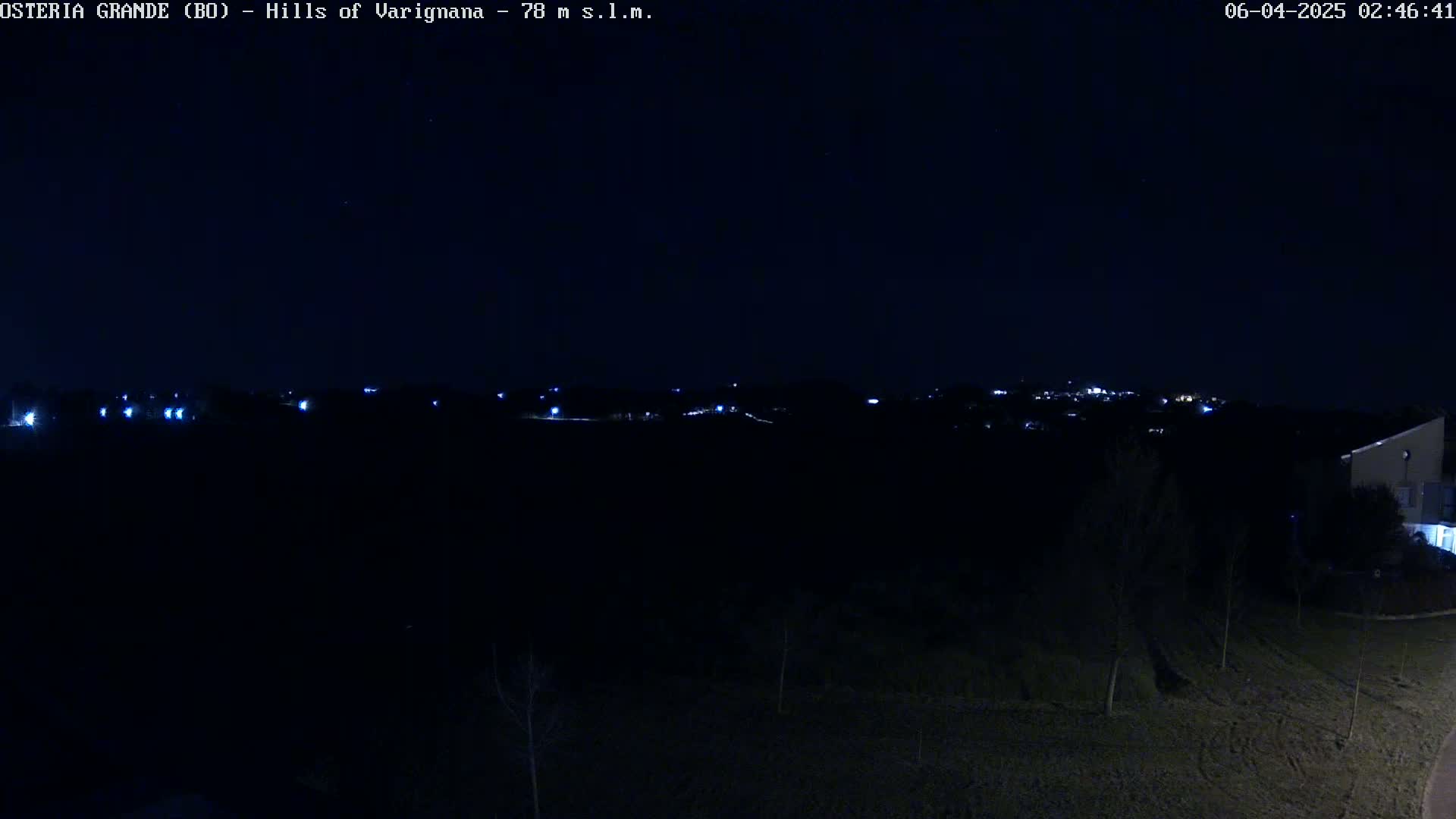A nighttime, dark view of distant lights on a hill, under a clear, dark sky.