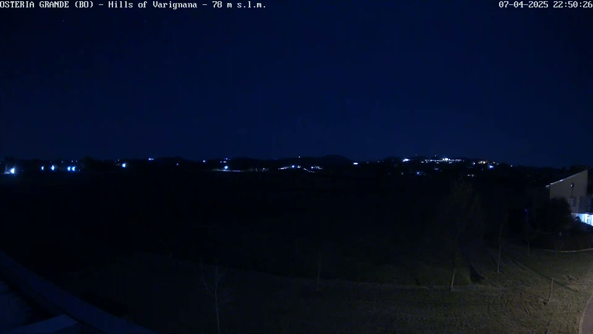 A nighttime view of dimly lit hills and houses under a dark sky.