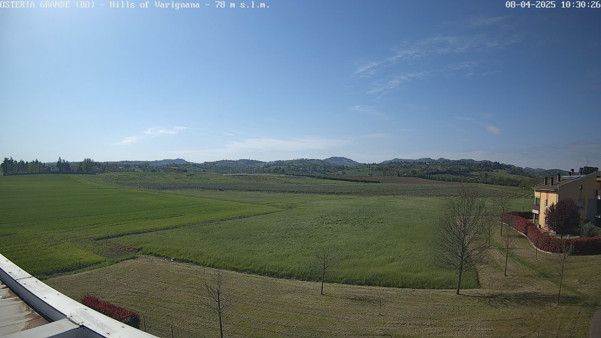 A wide, expansive view of rolling green hills and fields under a clear blue sky.