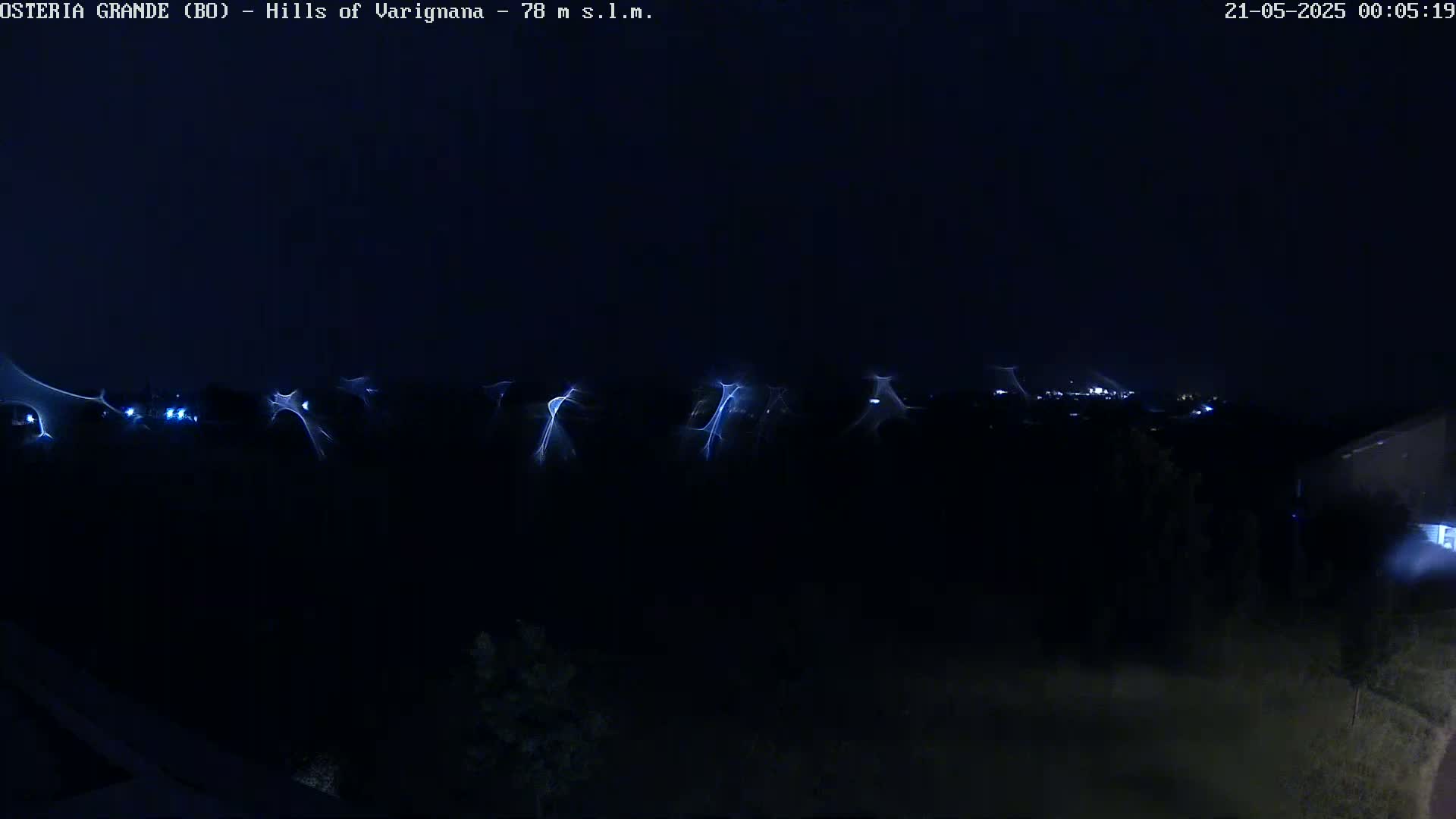 A nighttime long exposure shows streaks of light across a dark landscape, possibly from lightning or light trails.