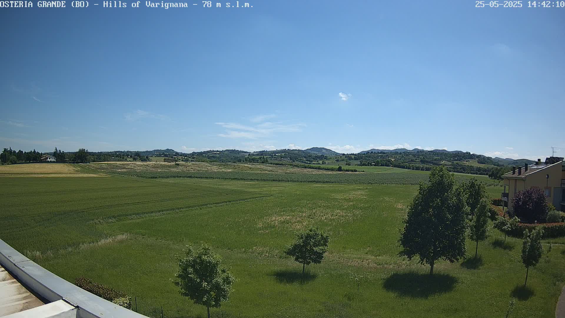 A sunny day reveals a vast expanse of green fields and rolling hills under a clear blue sky.