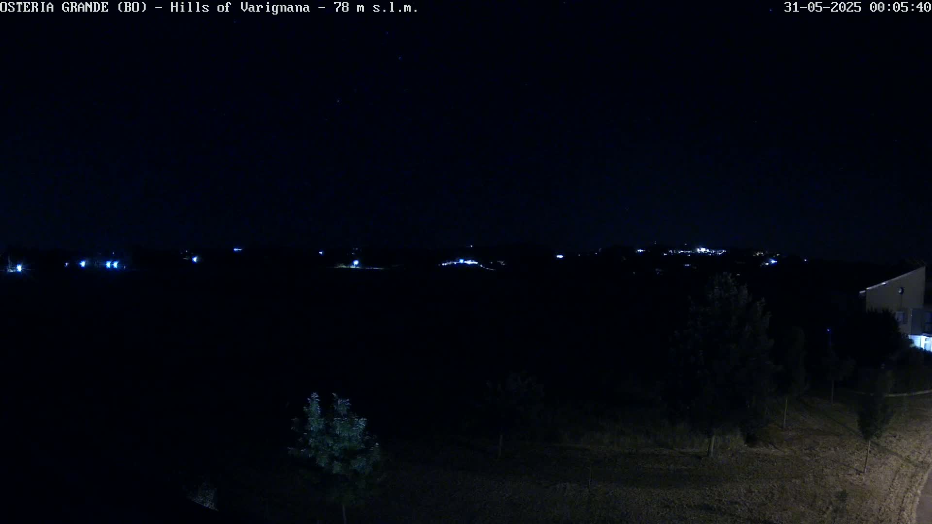 A nighttime view of dark hills and a few distant lights, under a clear, starlit sky.