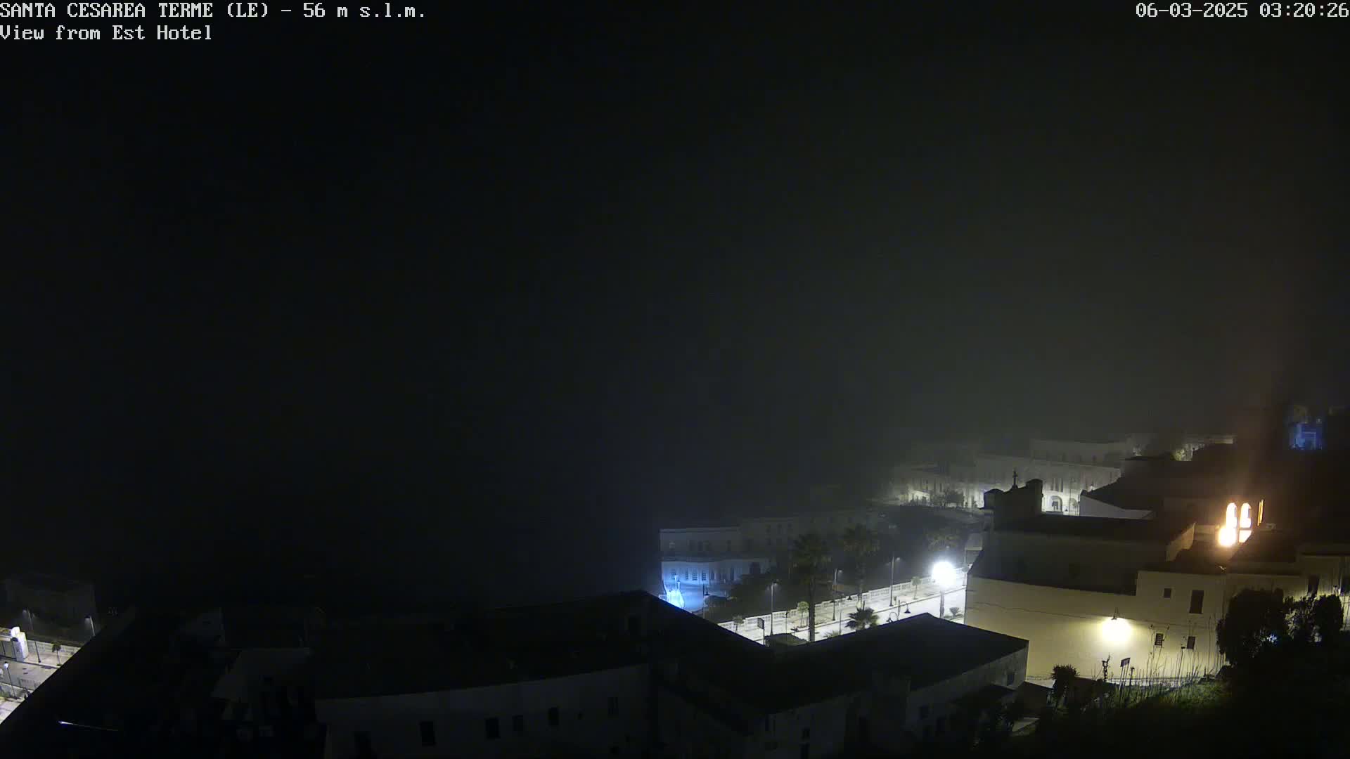 A nighttime, foggy view of a town with dimly lit buildings.