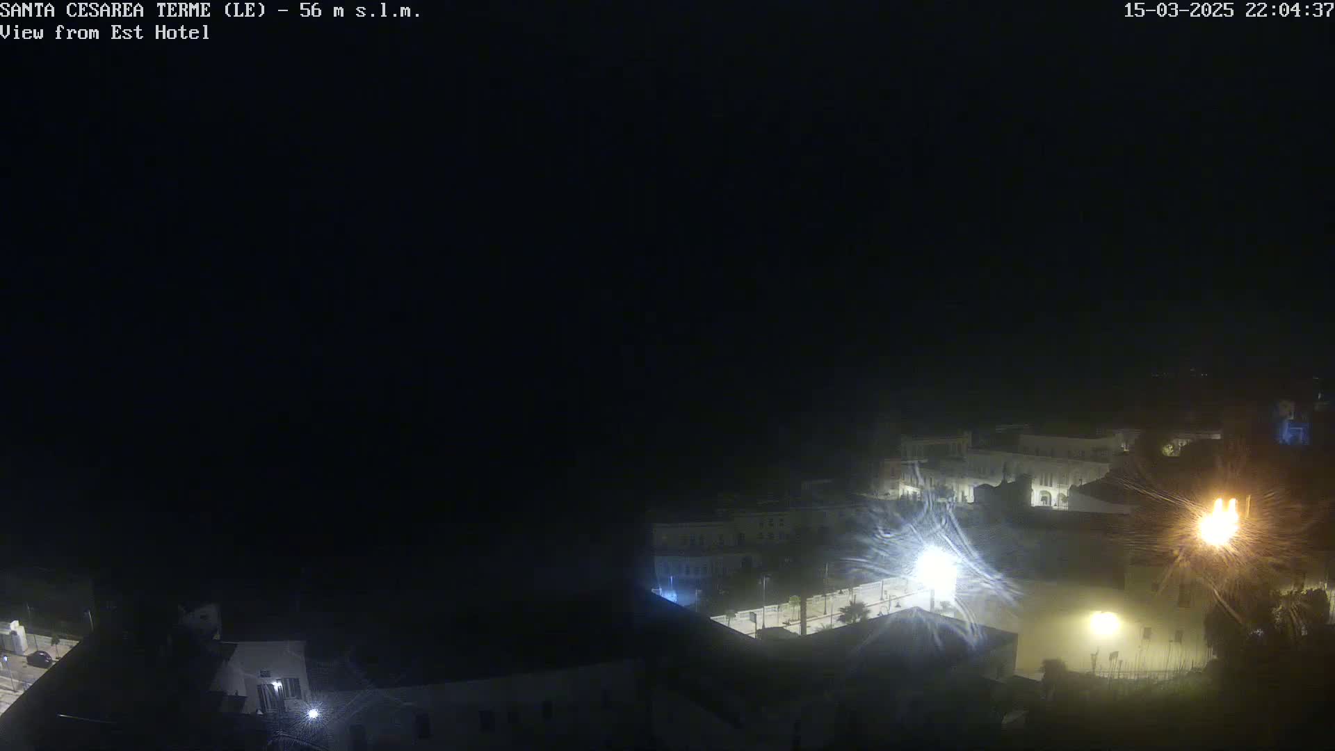A nighttime, hazy view of a town illuminated by streetlights.