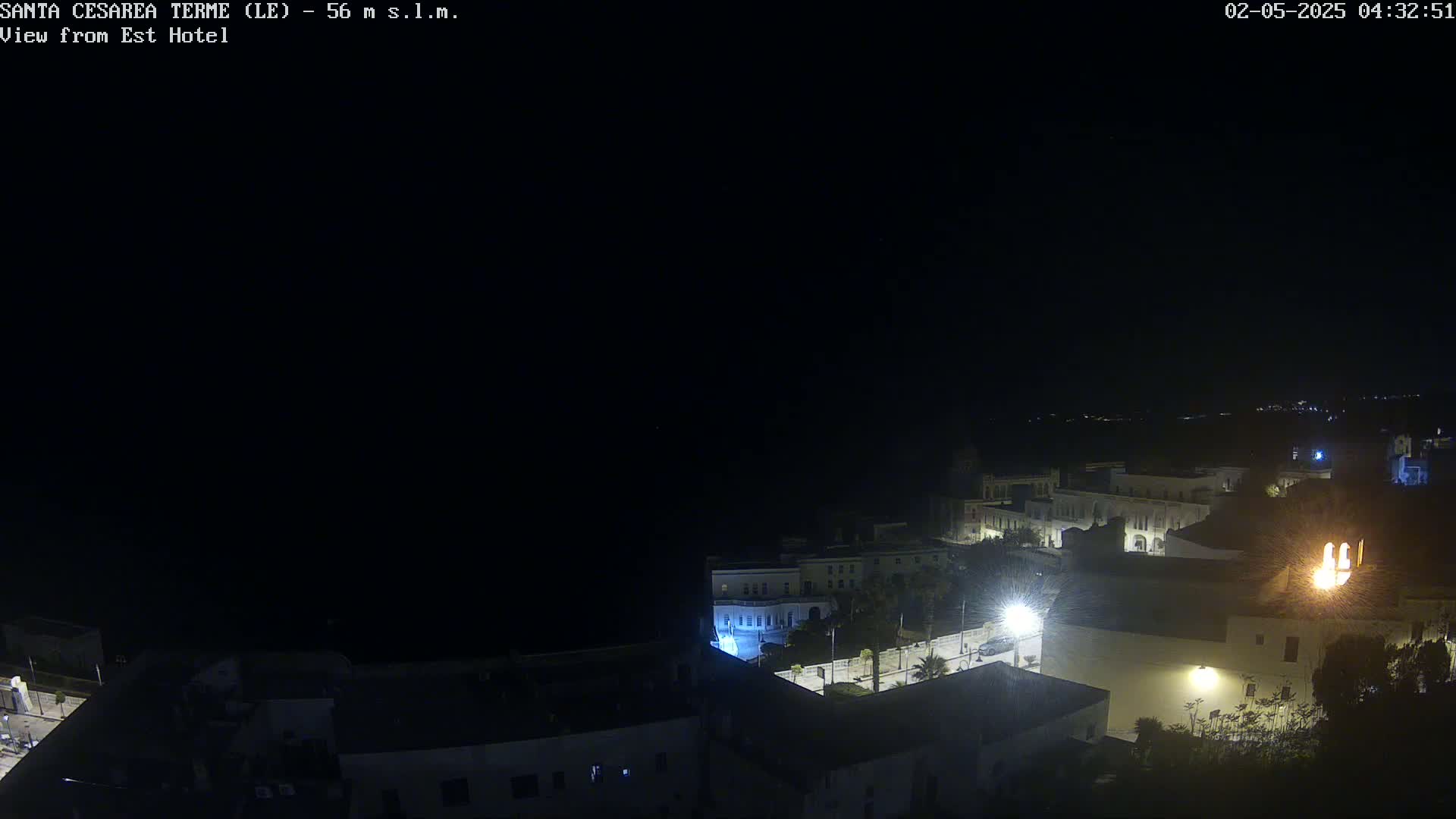 A nighttime, aerial view of a coastal town with dimly lit buildings and streets.