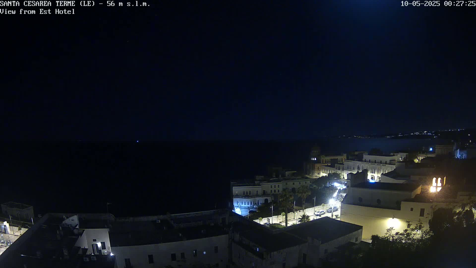 A nighttime, seaside town with dimly lit buildings is visible under a dark sky.