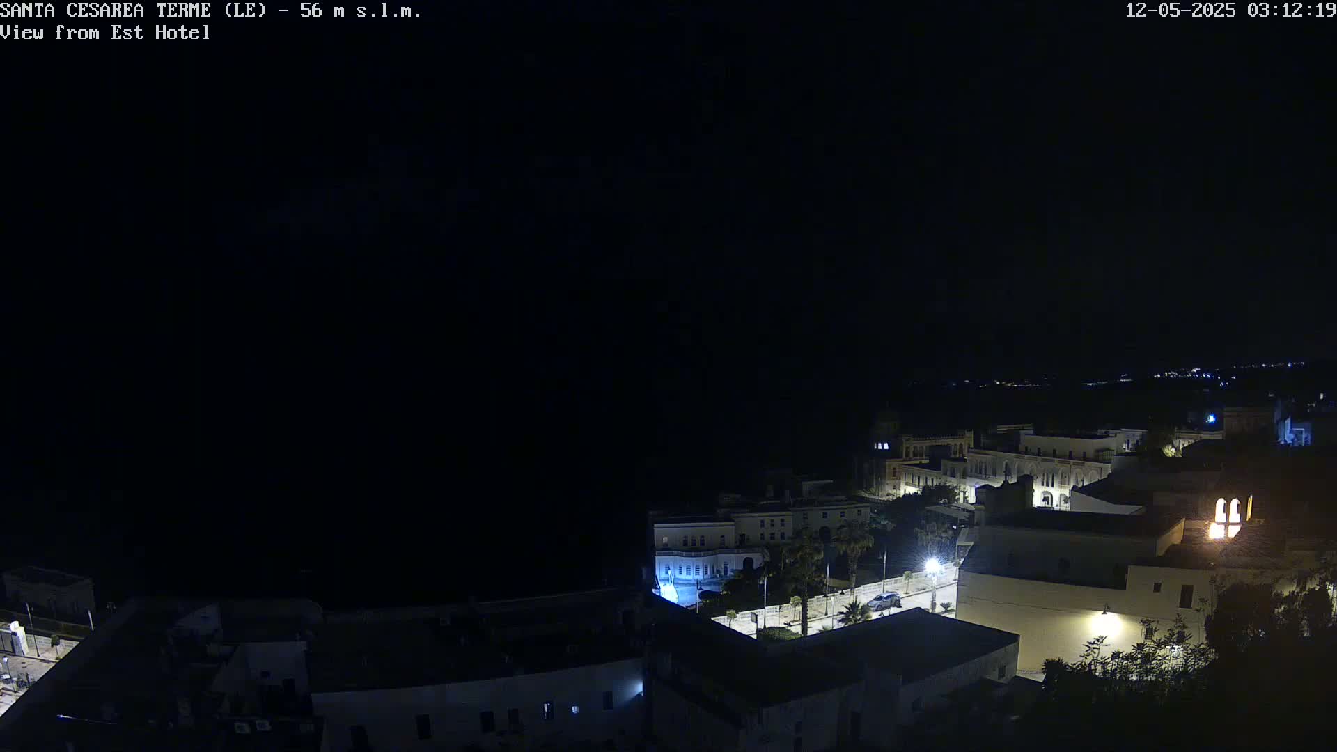 A nighttime, high-angle view of a coastal town with dimly lit buildings and streets.