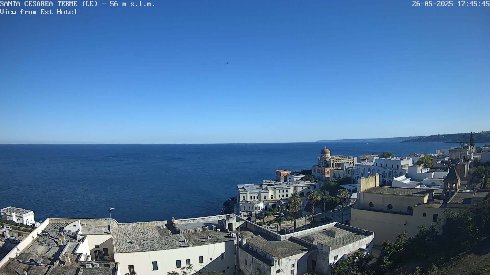 A clear, sunny day overlooking a coastal town and the deep blue sea.