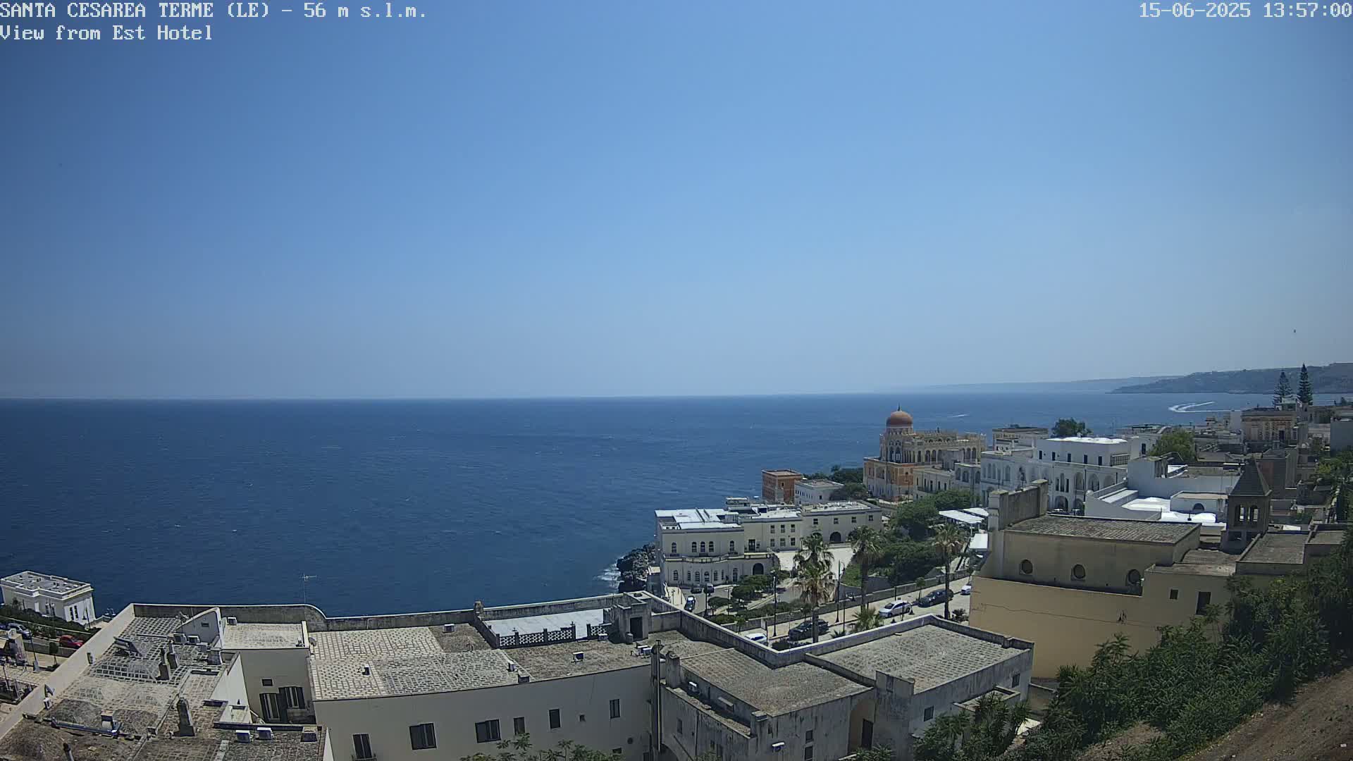 A coastal town with white buildings, overlooking a calm blue sea under a clear sky.
