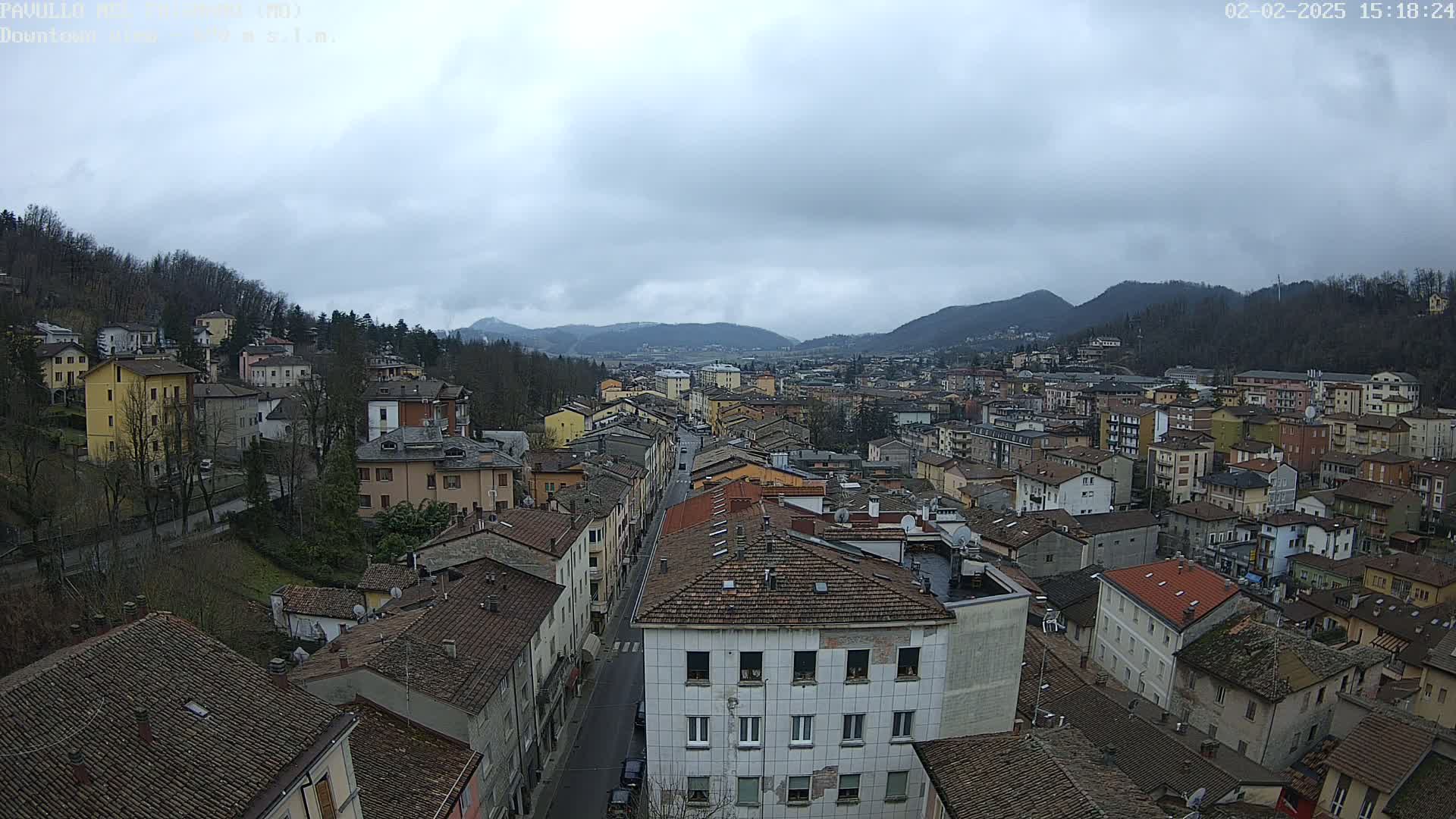 An aerial view of a town nestled in a valley, under a cloudy sky.