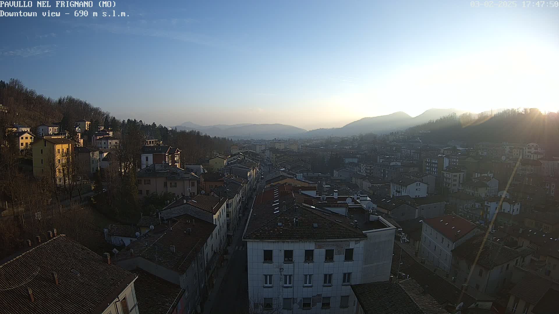 A high-angle view of a town nestled in a valley at sunset under a clear sky.