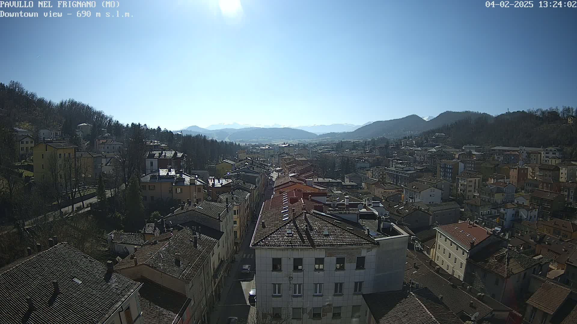 A sunny day reveals a sprawling town nestled in a valley, surrounded by hills and mountains.
