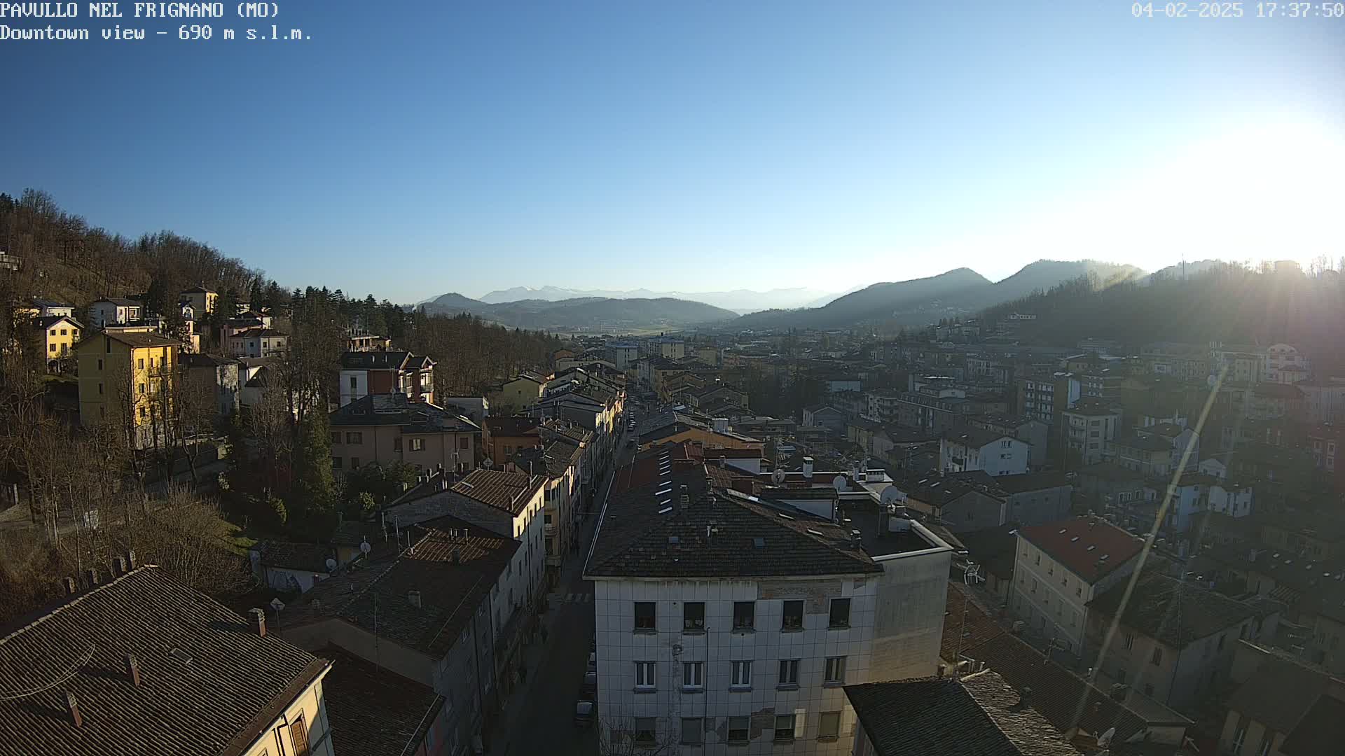 A sunny, high-angle view of a town nestled in a valley, surrounded by mountains.