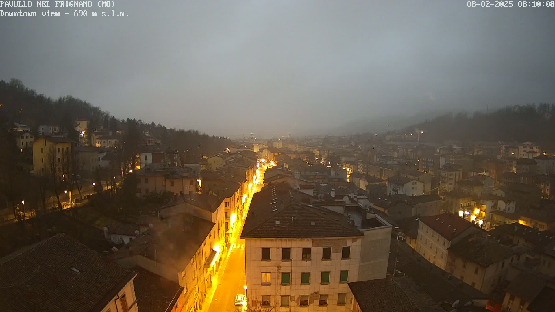 A foggy night view of a town with illuminated streets and buildings.