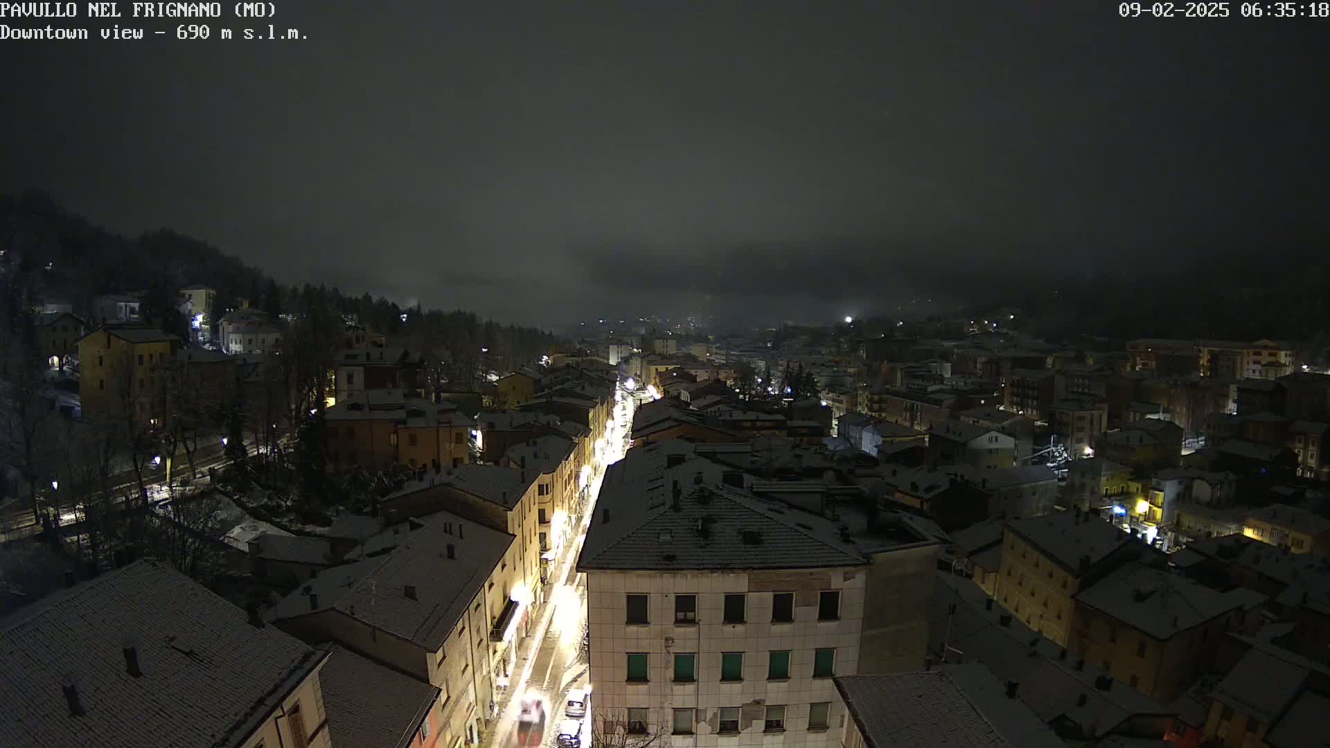 A snow-covered town is illuminated at night under a dark, cloudy sky.