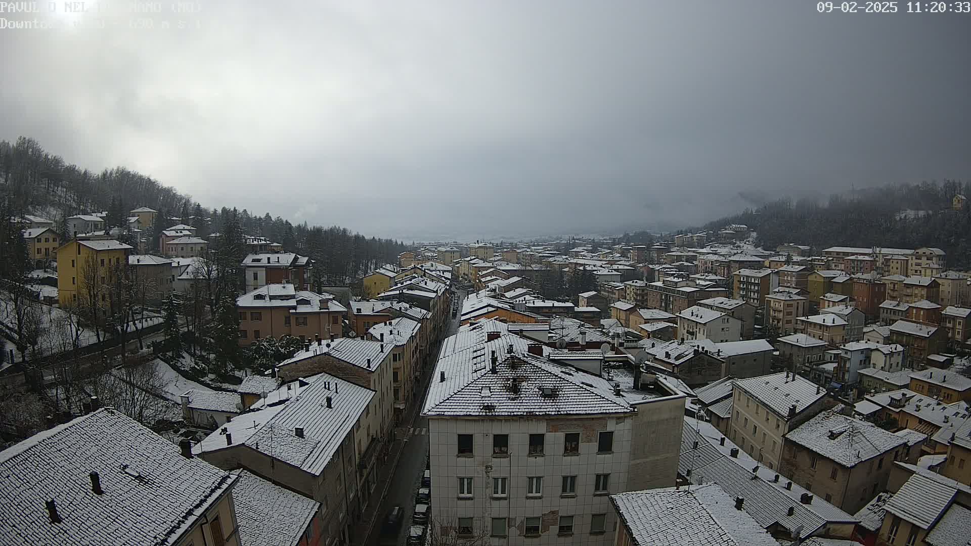 A snow-covered town nestled in a valley under a cloudy sky.