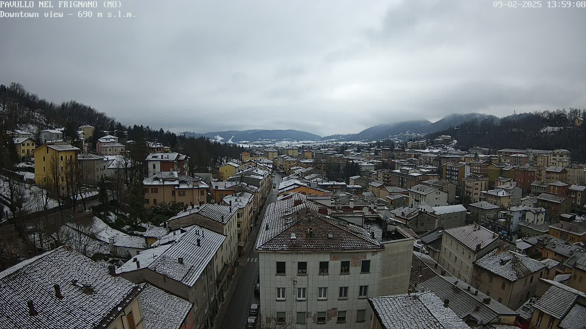 A snow-covered town nestled in a valley between mountains under an overcast sky.