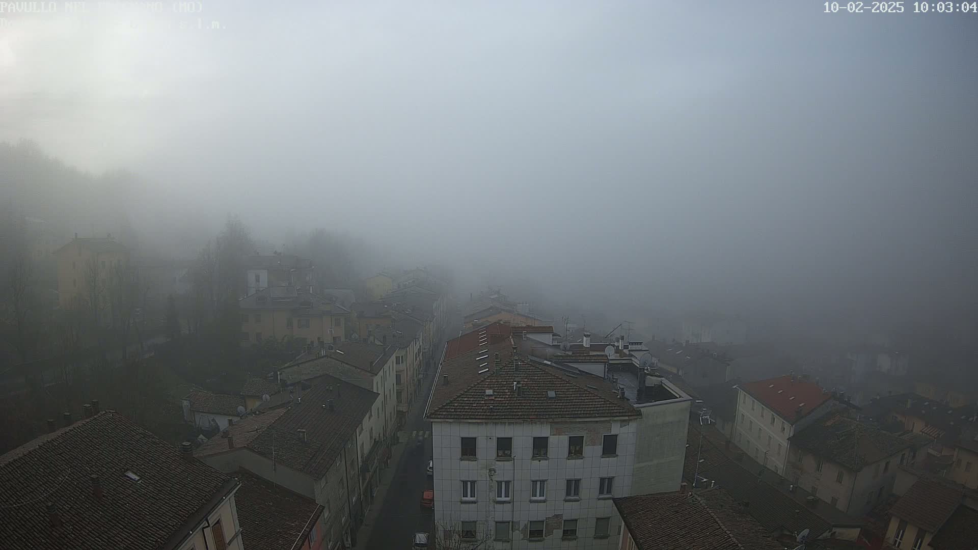 A foggy cityscape reveals a street lined with multi-story buildings.
