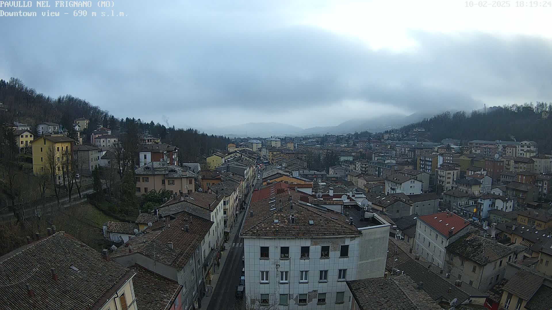 A high-angle view of a town nestled in a valley under a cloudy sky.