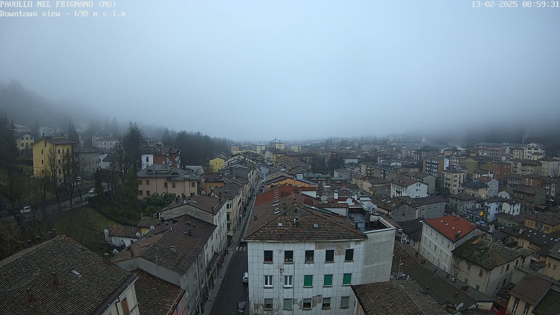 A foggy view of a town's downtown area, showing many closely-packed buildings with reddish-brown roofs.