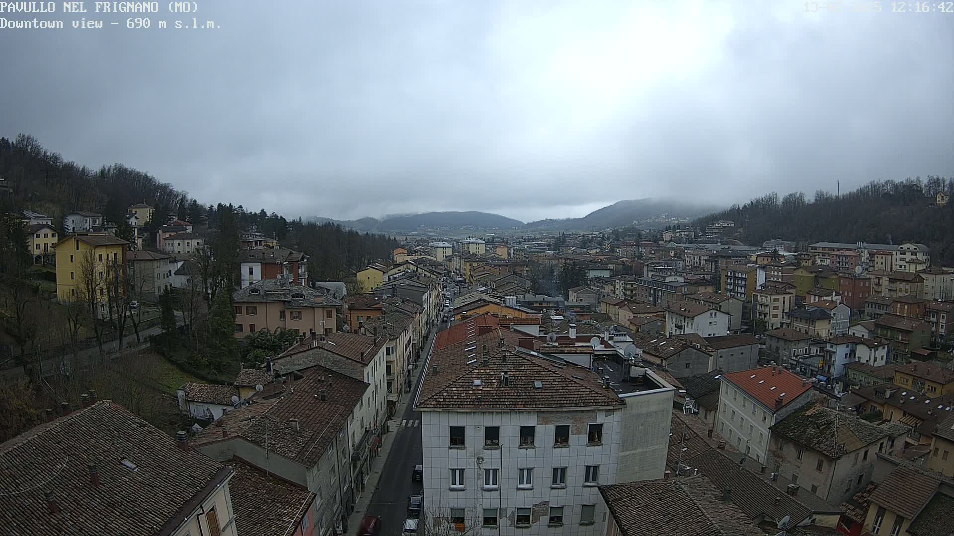 A sprawling town nestled in a valley under a cloudy sky, with a long street running through its center.