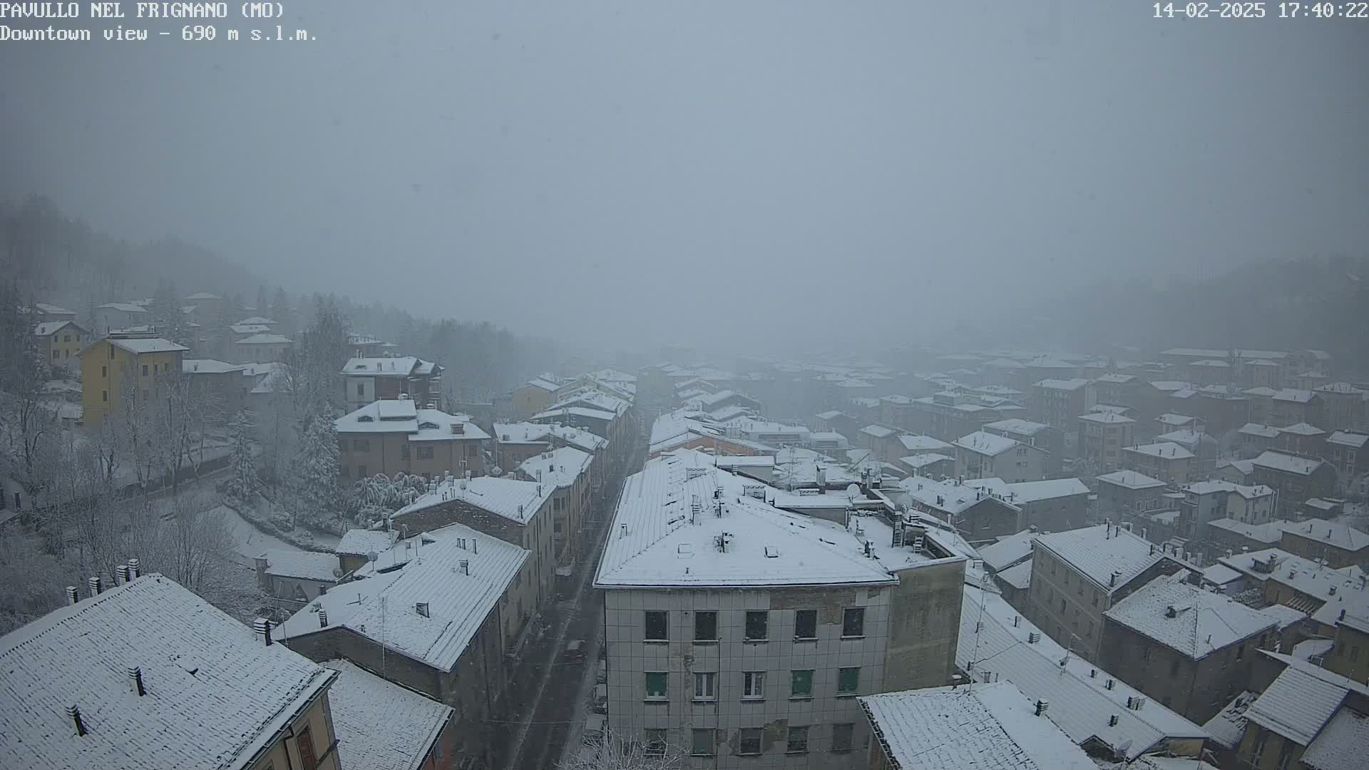 A snow-covered town is viewed from above in heavy snowfall.