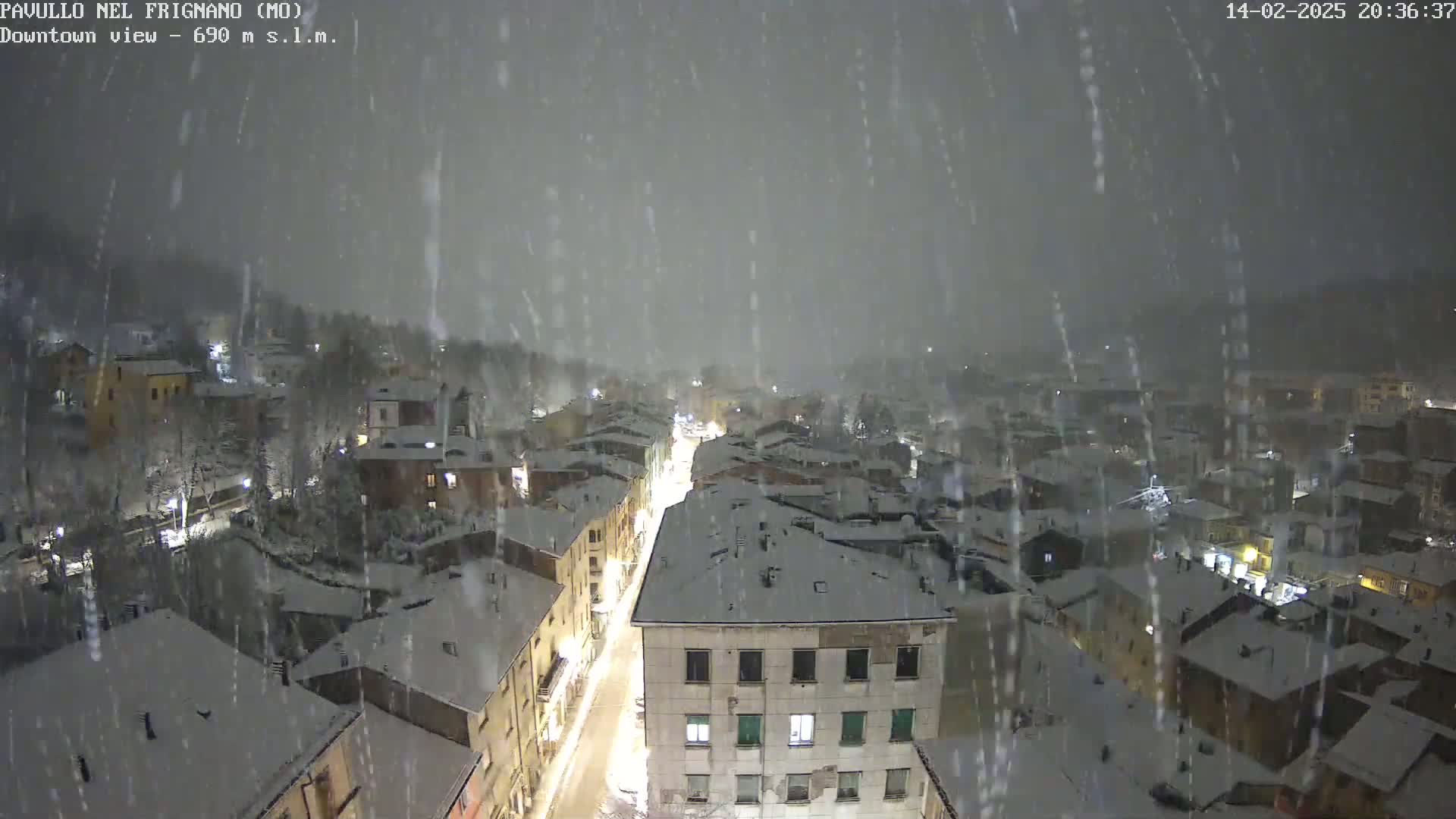 A snow-covered town is viewed from above at night during a heavy snowfall.