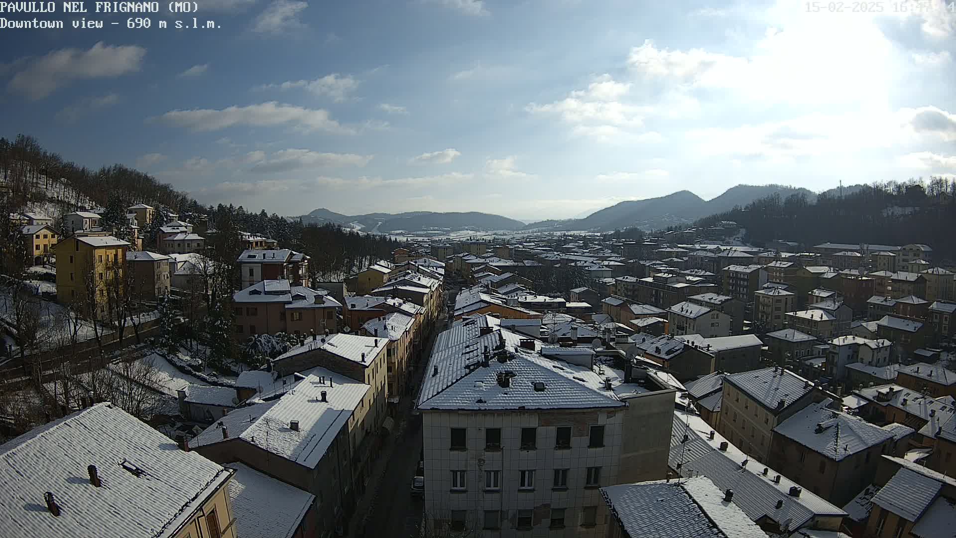 A snow-covered town nestled in a valley under a mostly sunny sky.