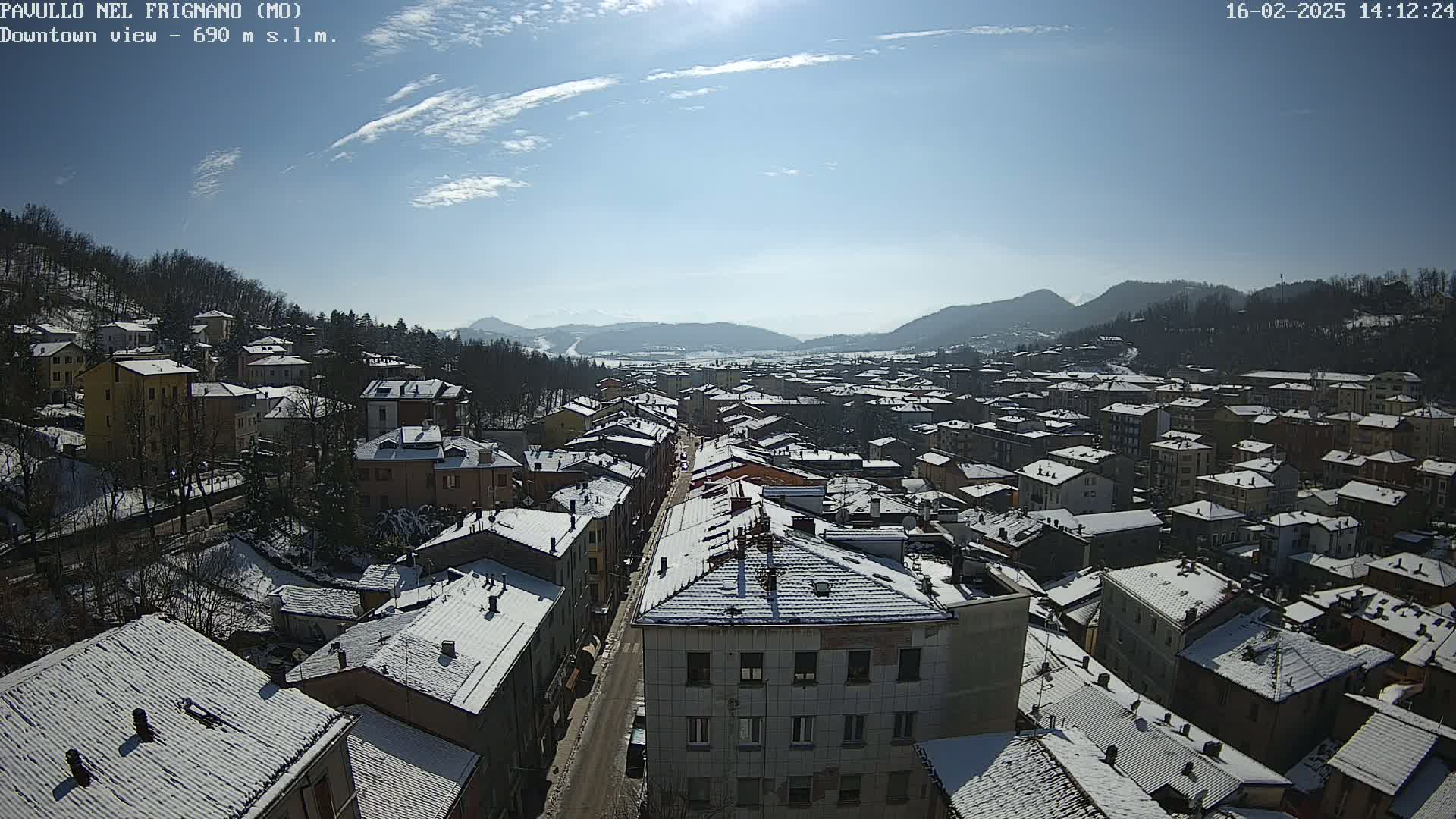 A snow-covered town nestled in a valley under a bright, sunny sky.