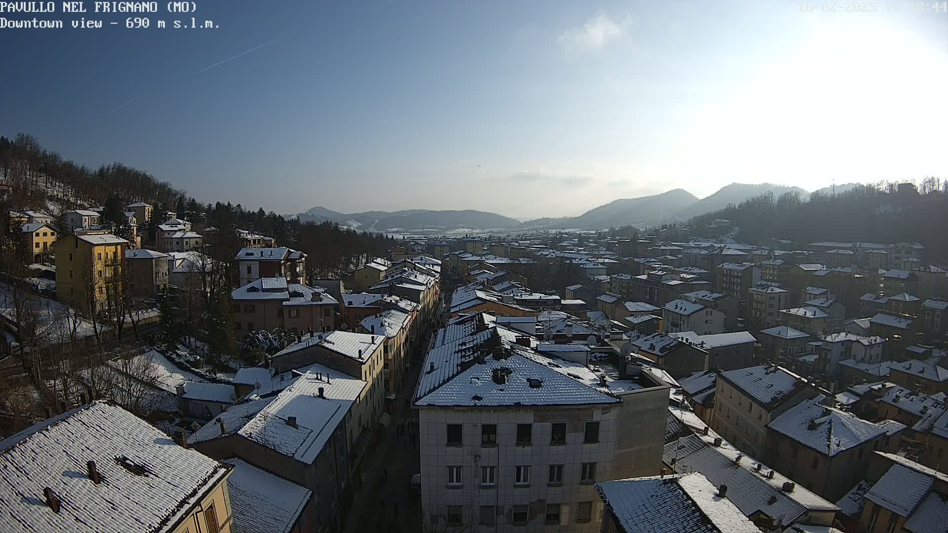 A snow-covered town nestled in a valley between mountains on a sunny day.