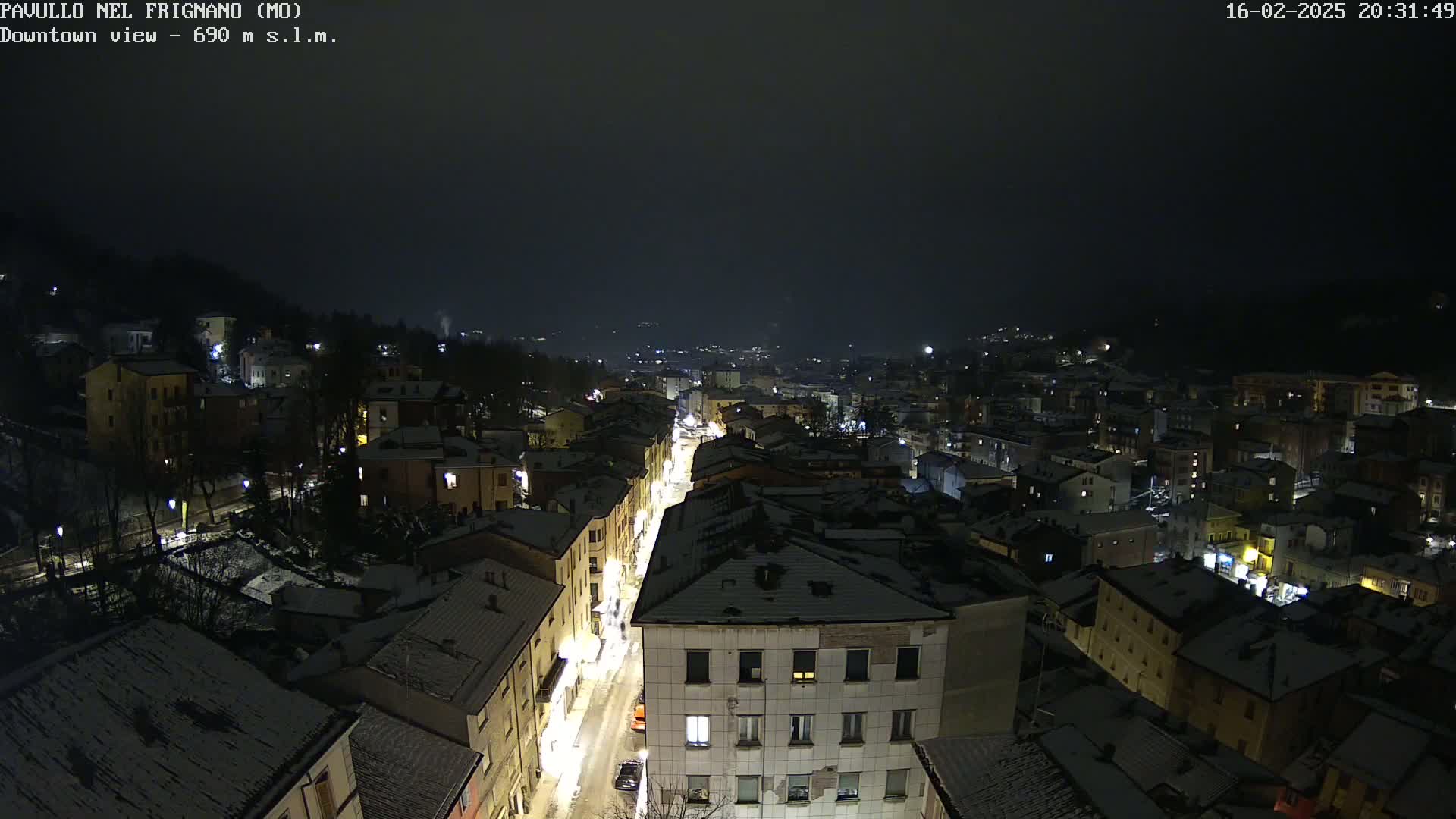 A nighttime aerial view of a snow-covered town, with dimly lit streets and buildings.