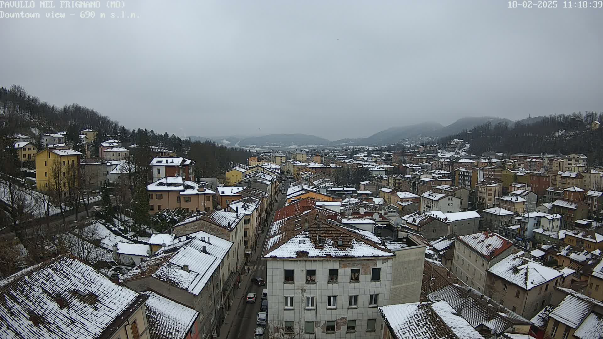 A snow-covered town nestled in a valley between mountains on an overcast day.