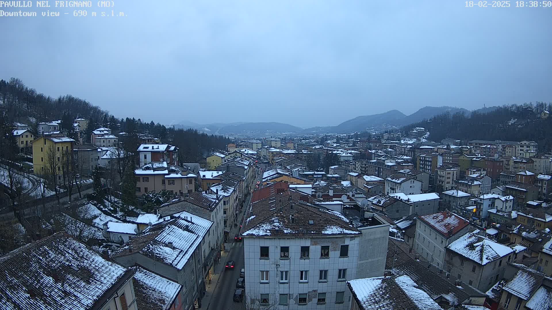 A snow-covered town nestled in a valley under a twilight sky.