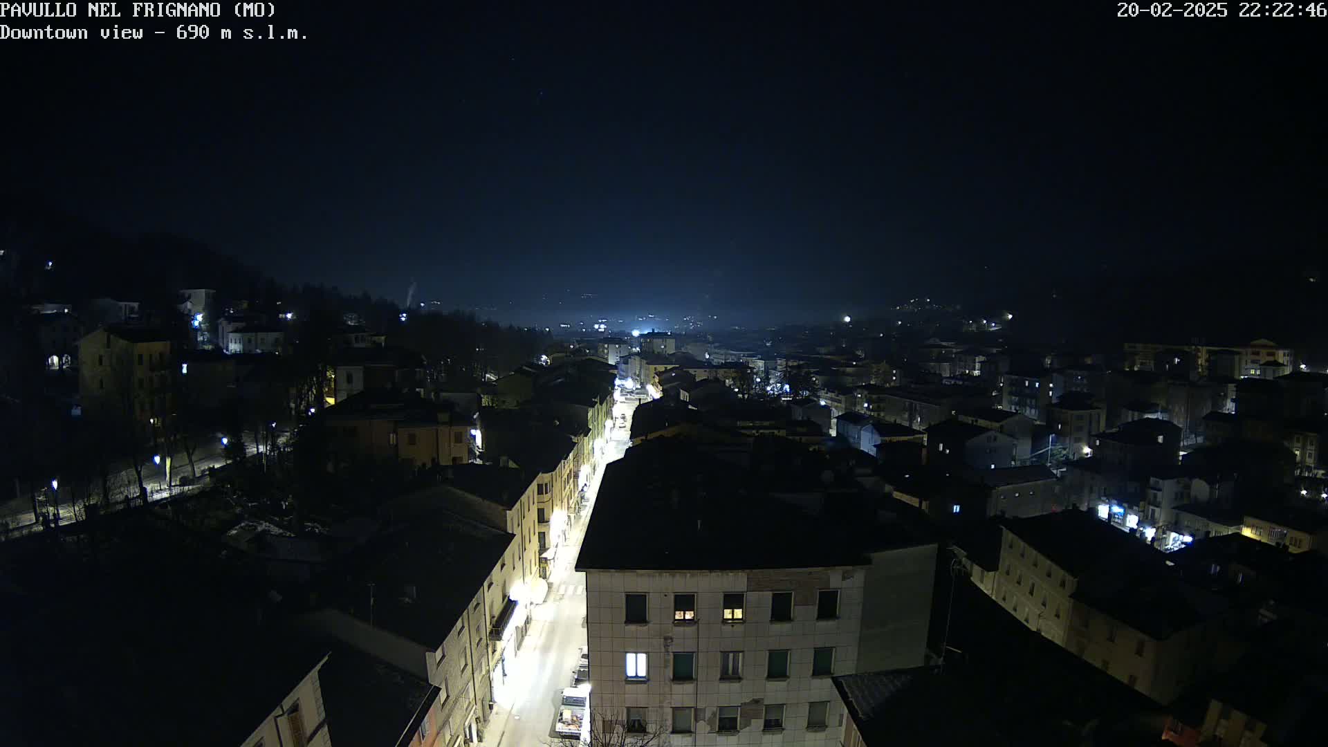 A nighttime, high-angle view of a town with dimly lit buildings and streets.