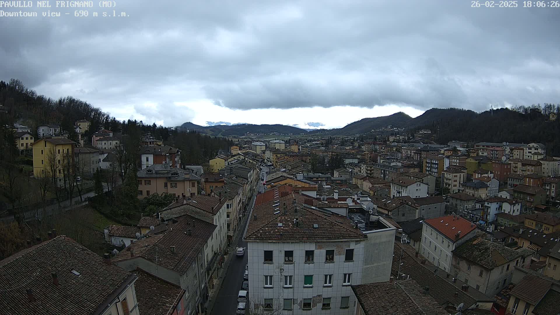 A view of a town nestled in a valley under a cloudy sky.