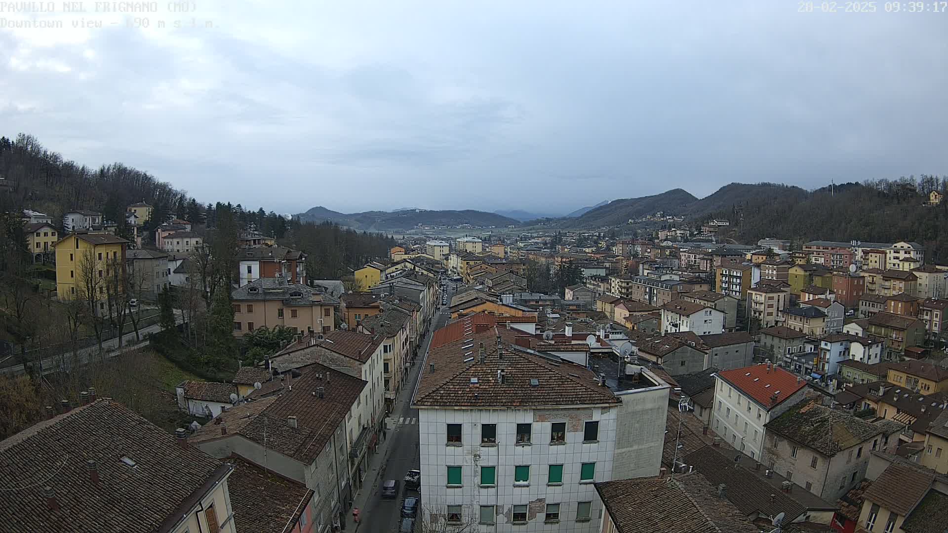 An aerial view of a town nestled in a valley, under a cloudy sky.