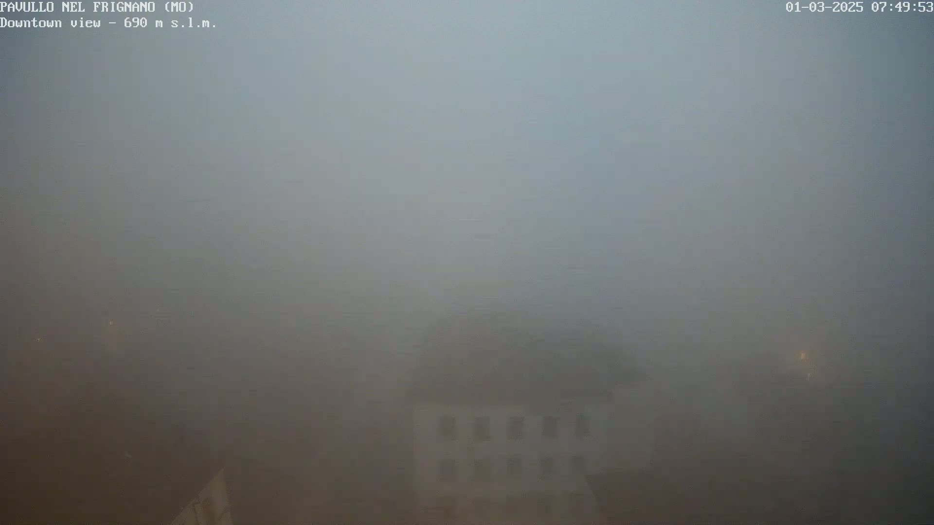 A thick fog obscures the view of a building and its surroundings.