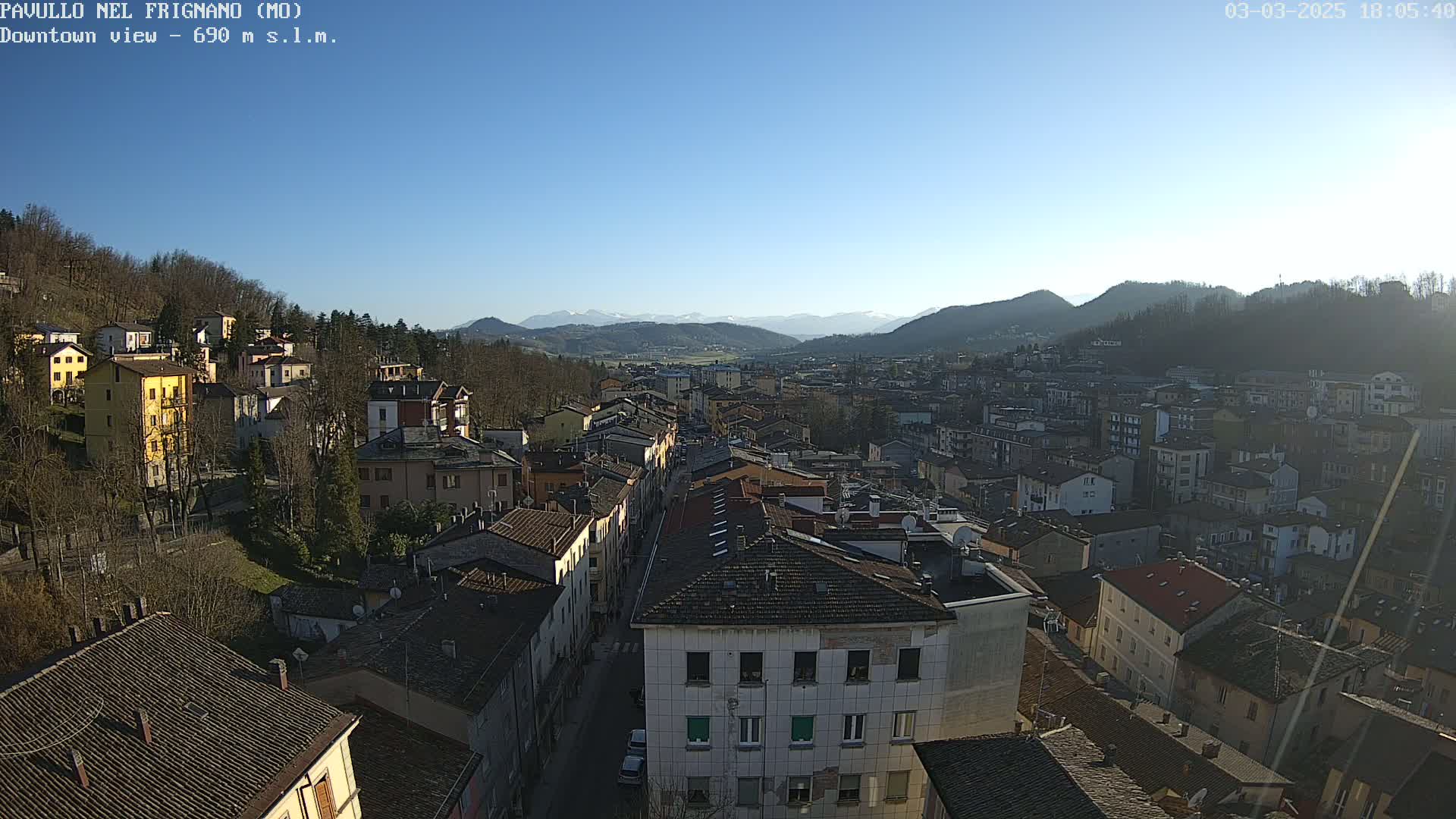 A high-angle, long shot of a town nestled in a valley, under a clear blue sky.