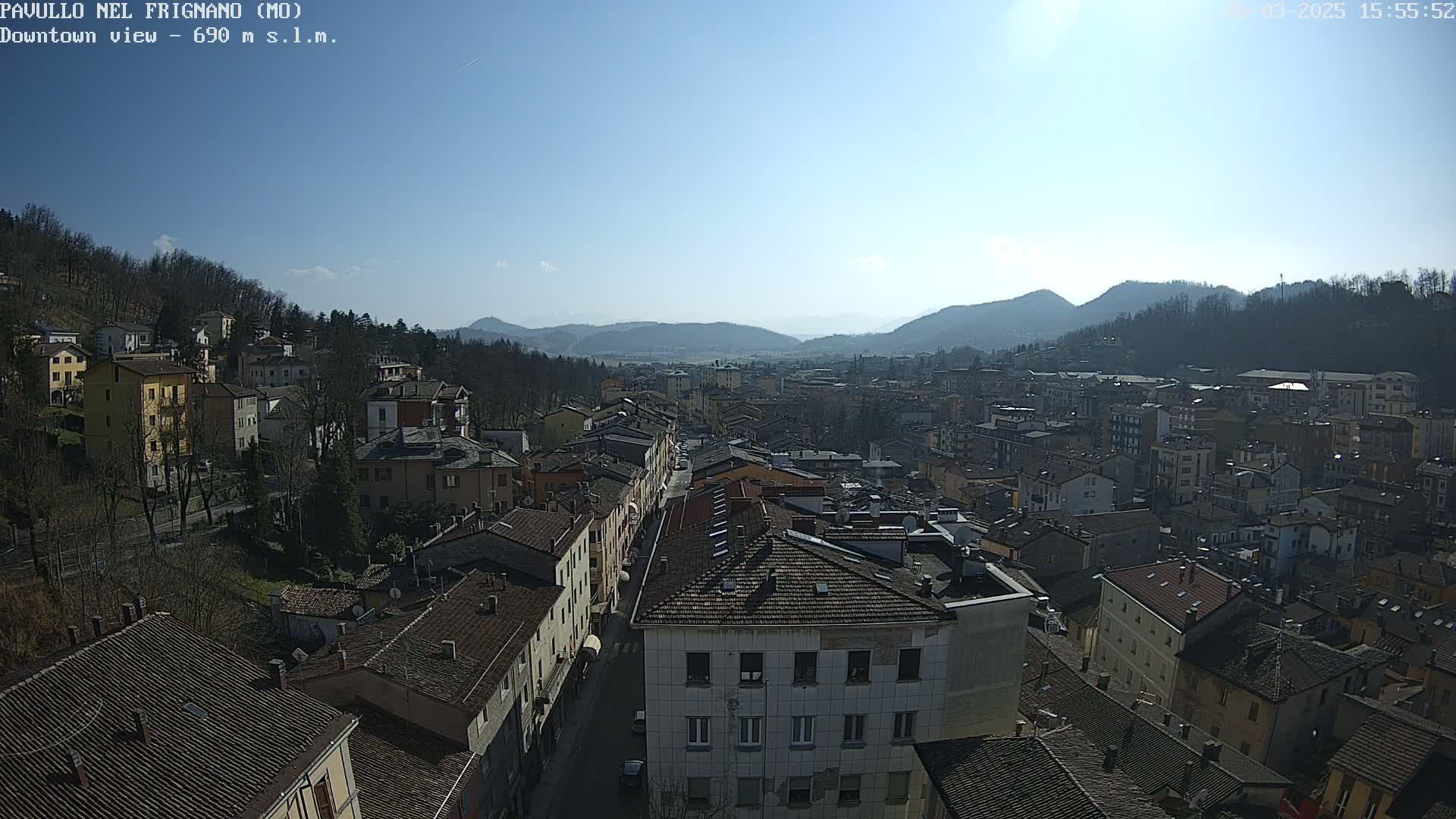 A sprawling town nestled in a valley between mountains on a sunny day.