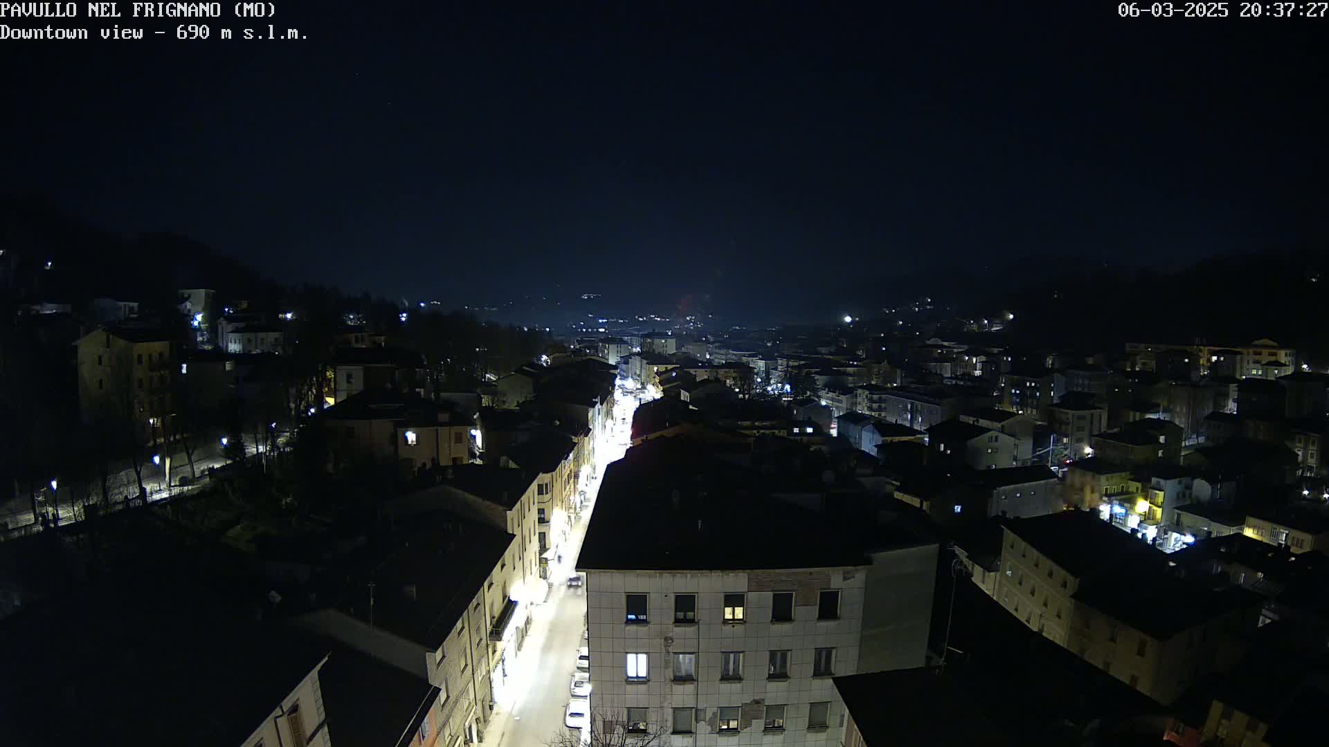 A nighttime, high-angle view of a town with illuminated streets and buildings under a dark sky.