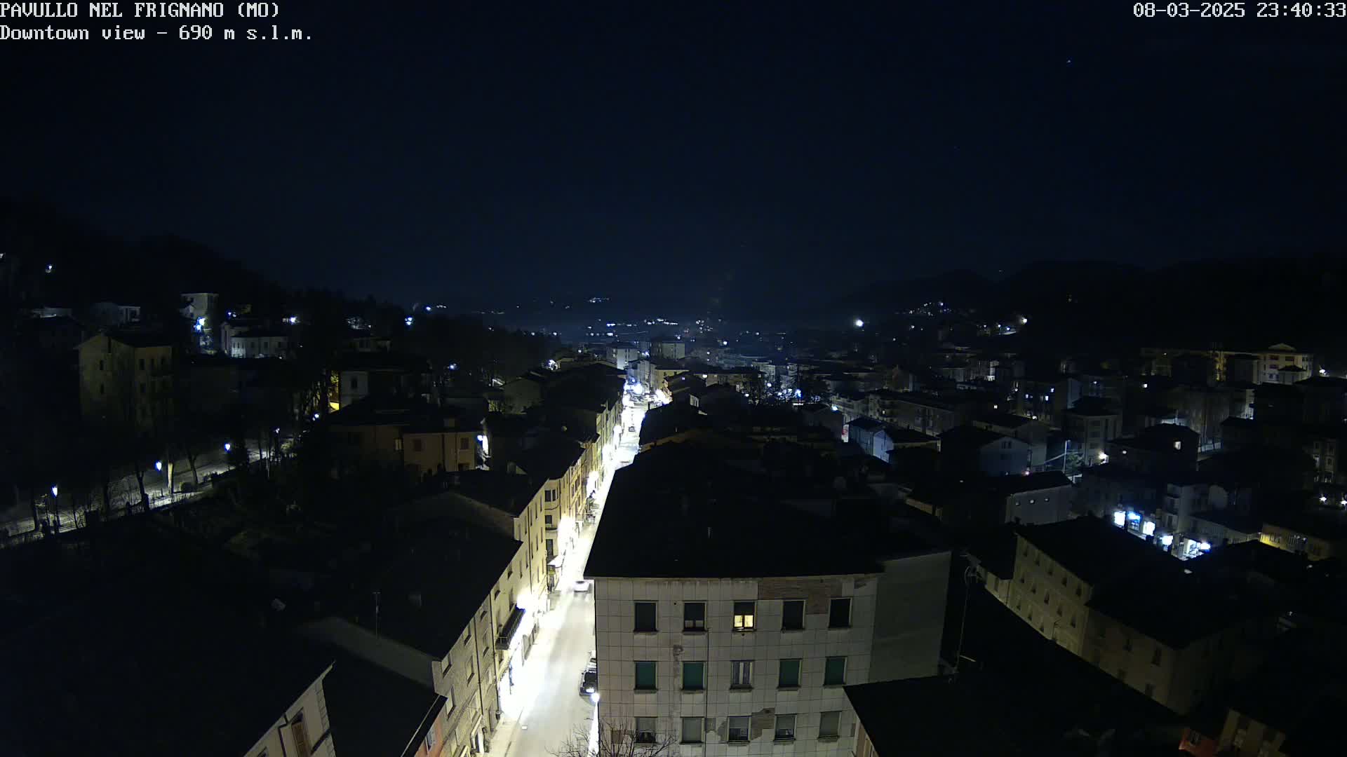 A nighttime, high-angle view of a town's illuminated streets and buildings under a clear, dark sky.