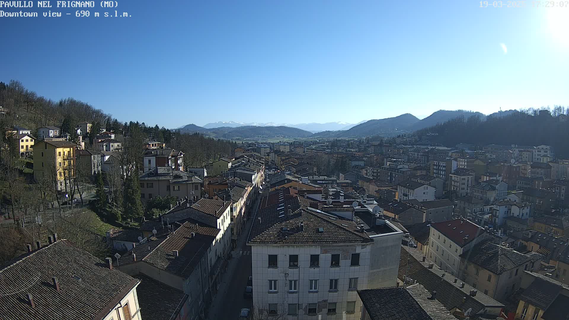 A clear, sunny day reveals a sprawling town nestled in a valley, surrounded by mountains.
