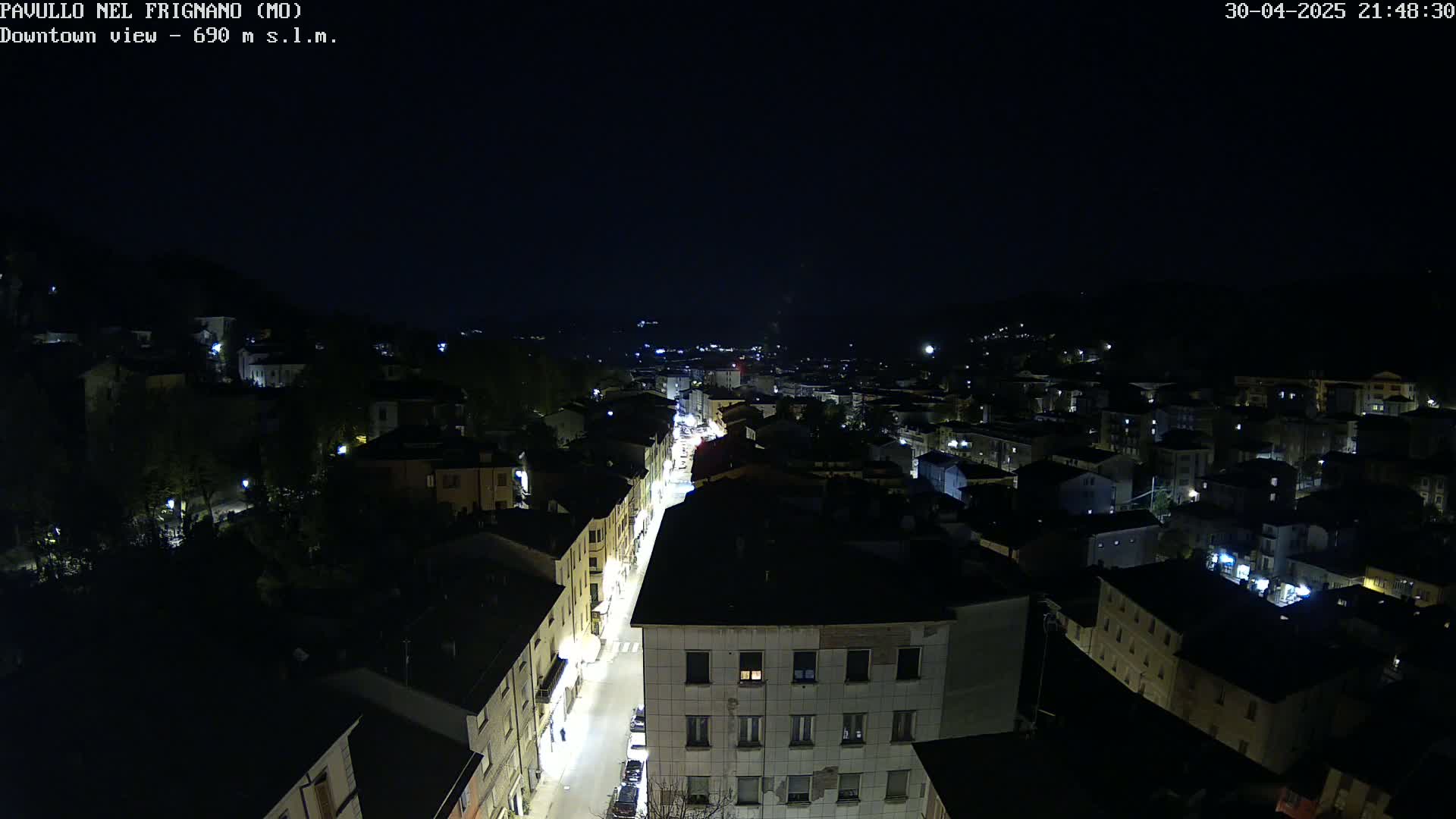 A nighttime, high-angle view of a town's streets and buildings illuminated by streetlights.