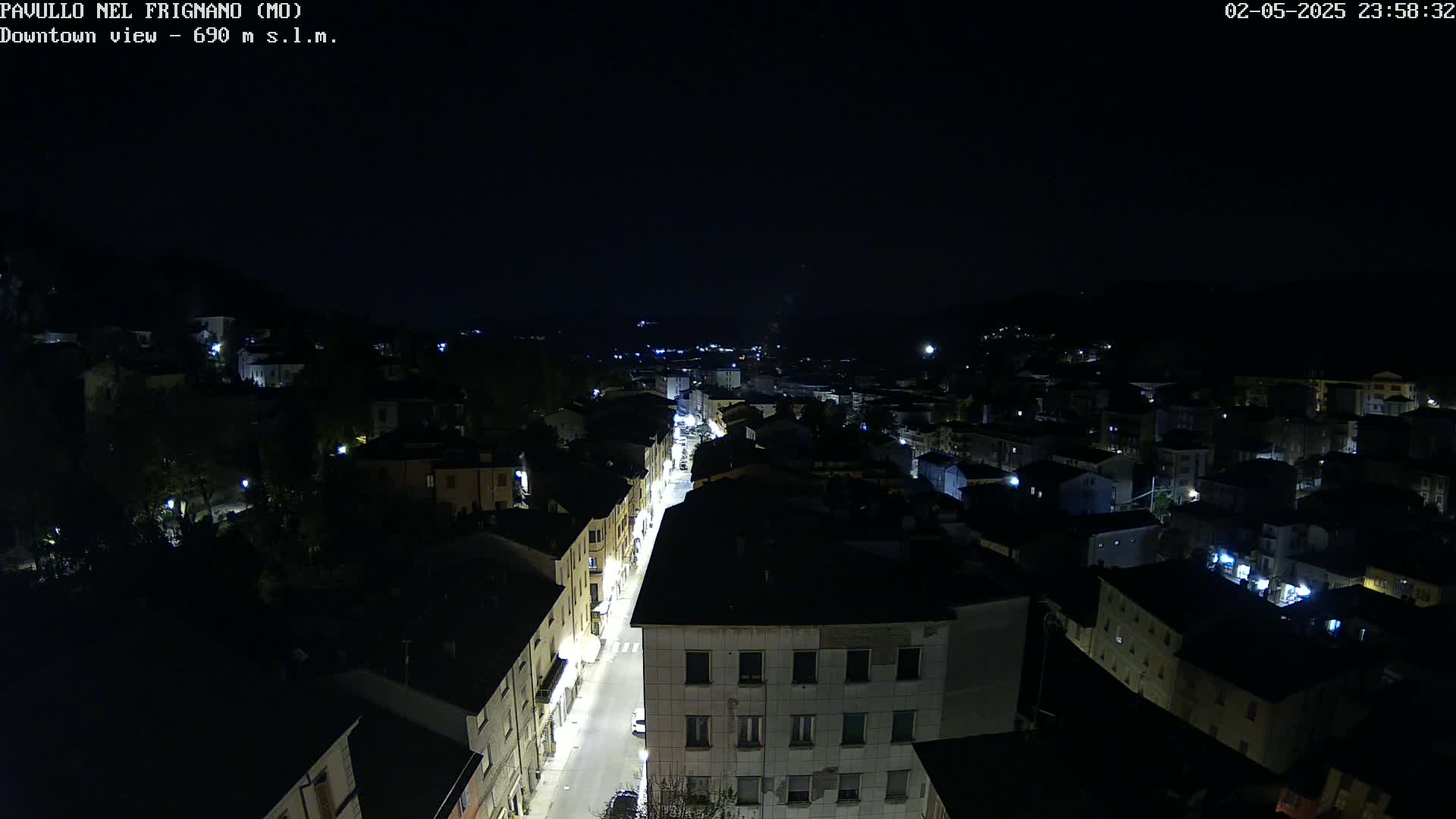 A nighttime, high-angle view of a town's street and buildings illuminated by streetlights.