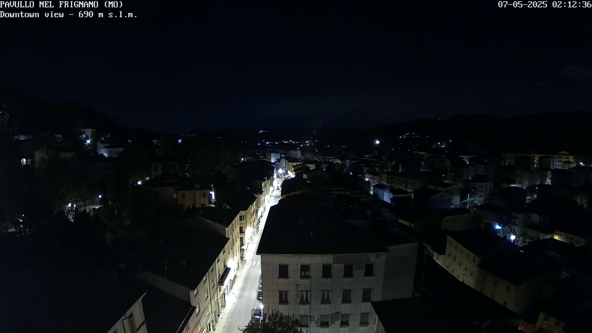 A nighttime, high-angle view of a town's illuminated streets and buildings under a clear, dark sky.