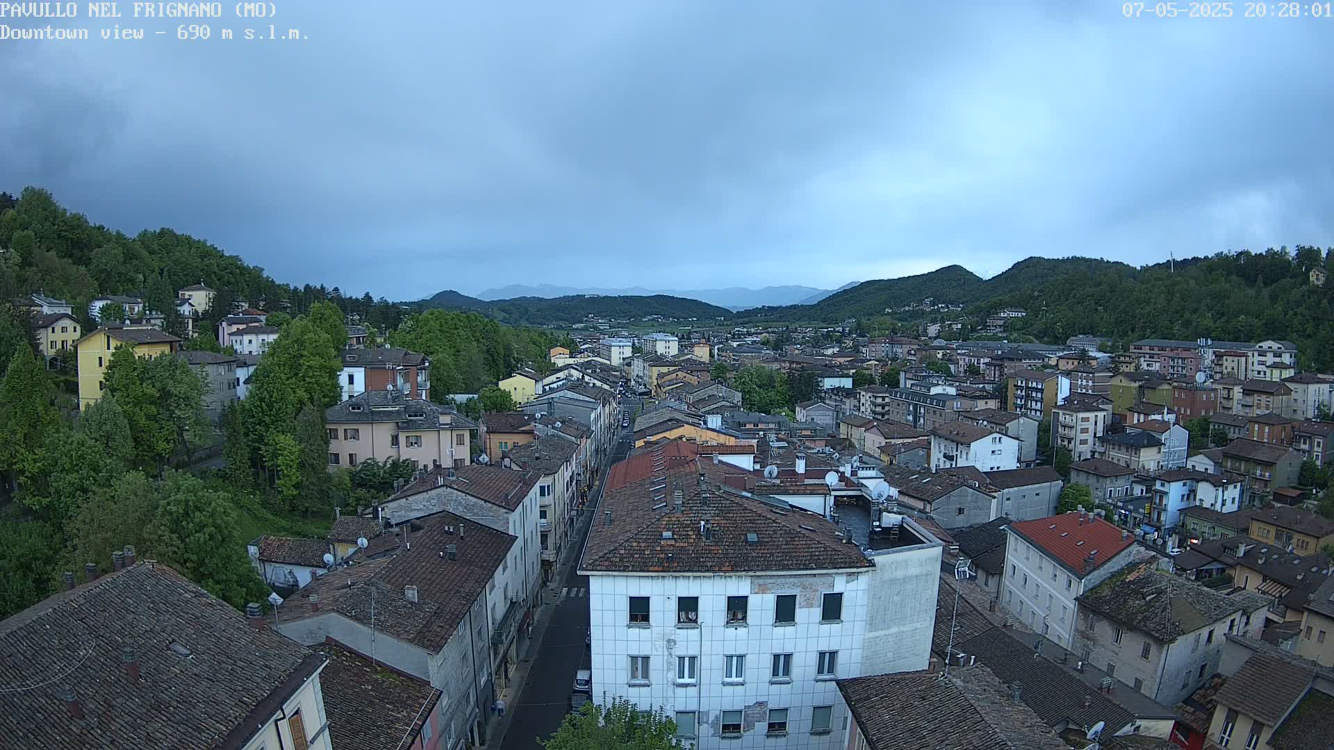 An elevated view of a town nestled in a valley under a mostly cloudy sky.